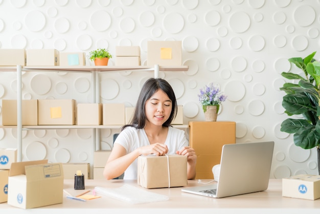 Asian Women business owner working at home with packing box on workplace