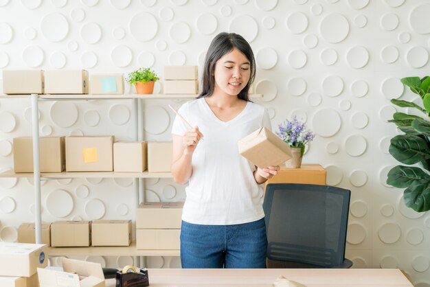 職場で梱包箱を自宅で働くアジア女性ビジネスオーナー
