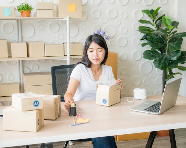 Asian Women business owner working at home with packing box on workplace