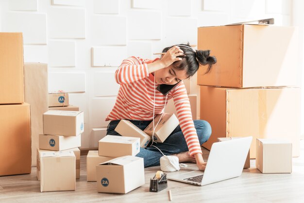 Asian Women business owner working at home with packing box on workplace