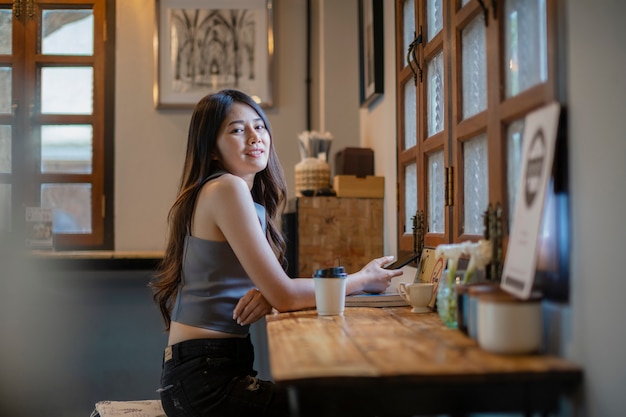 アジアの女性がコーヒーショップで携帯電話の情報を確認する