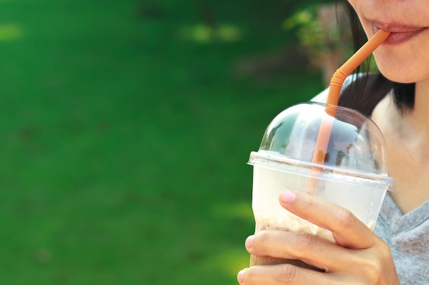 Asian women drinking Iced coffee with milk in plastic glass.