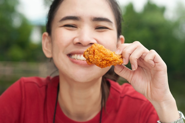 Asian women eating chicken wing sitting on table