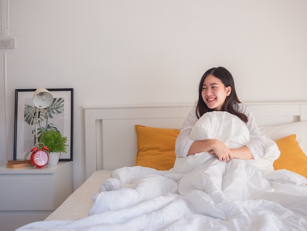 Asian women embrace pillows on bed in the morning