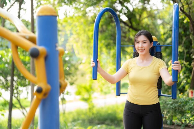 アジアの女性が公園の遊園地を使って運動する健康的な運動と自分自身のケアのコンセプト