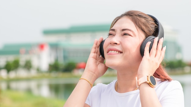 アジアの女性幸せな屋外で音楽を聴く