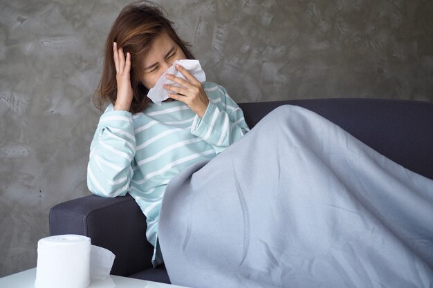 アジアの女性は激しい頭痛と鼻水があります。蚊に刺された後