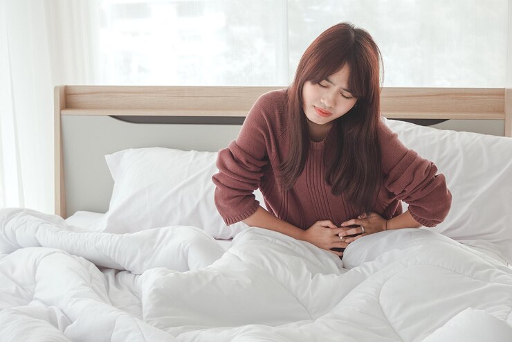 Photo 아시아 여성은 복통과 침대에서 불편함을 느낍니다.
