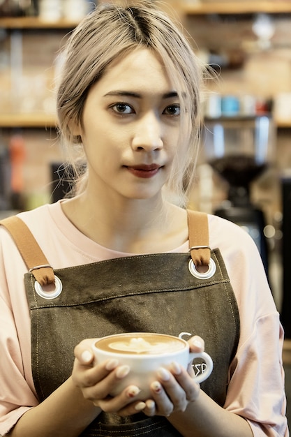カフェでコーヒーカップを保持しているアジアの女性