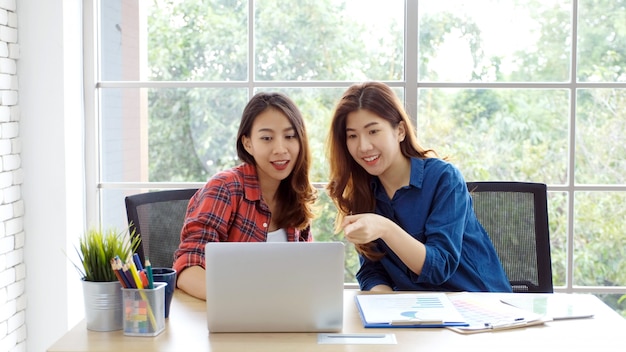 Asian women at home office, happy two young asian women working with laptop computer at office, asian friends working together with happiness, asia girl working at home, online education