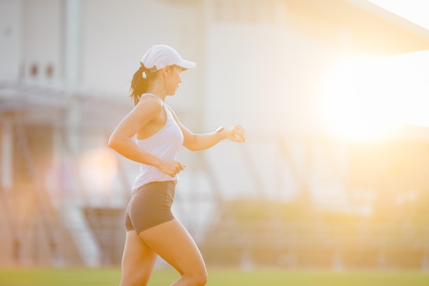 Asian women is watching the sport watch or smart watch for\
jogging on stadium track