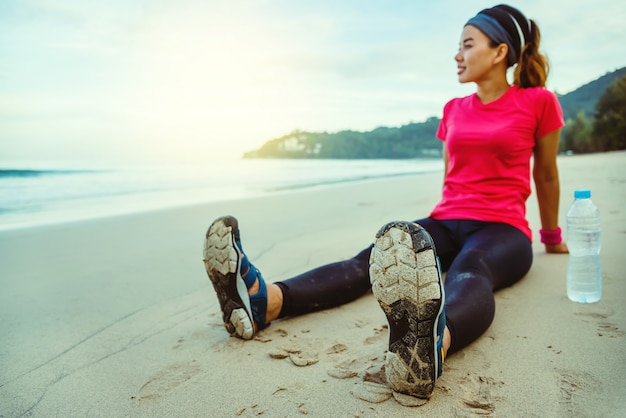 アジアの女性がビーチでトレーニングをジョギング