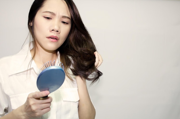 Donne asiatiche che cercano la caduta dei capelli che cadono sulla spazzola per capelli con una faccia preoccupata