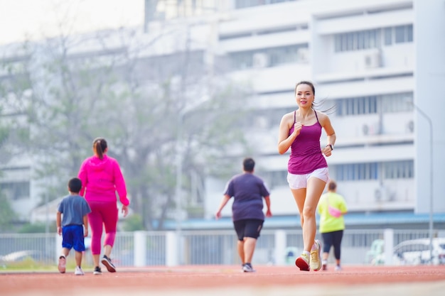 Donne asiatiche di mezza età in esecuzione durante la mattina di sole sulla pista dello stadio