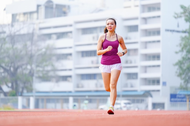 Asian women middle aged running during sunny morning on stadium track