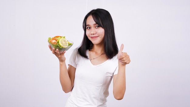 Asian women and okay finger at a bowl of fresh mixed vegetables salad with isolated white surface