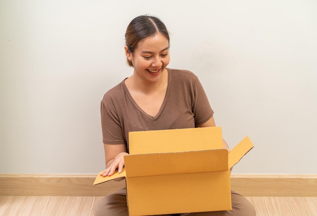 Asian women opening parcel box package shipment service and\
delivery courier concept