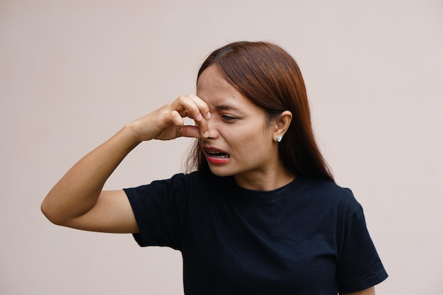 Asian women pinch their noses with their hands to avoid foul odors