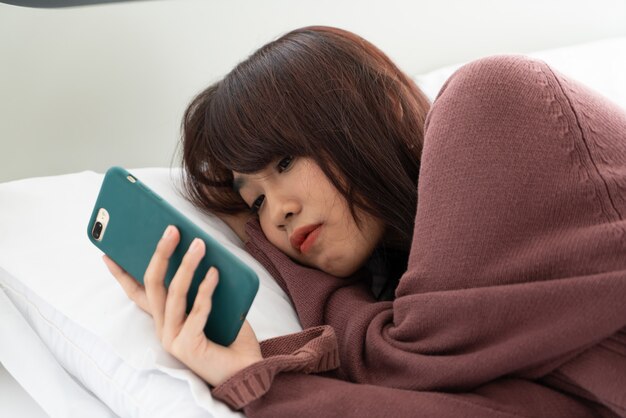 Asian women playing smartphone on bed