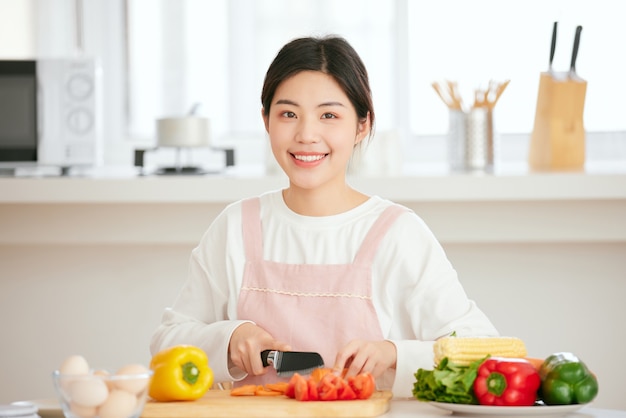 アジアの女性は新鮮な果物の野菜と一緒に台所のテーブルでリラックス