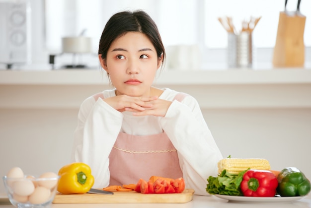 Asian women relax at the kitchen table with fresh fruit vegetables