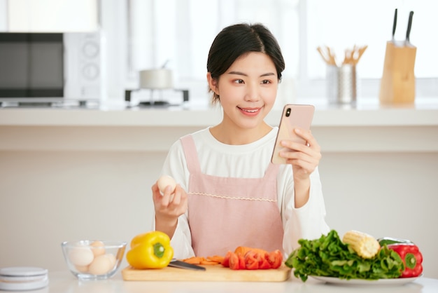 Asian women relax at the kitchen table with fresh fruit vegetables