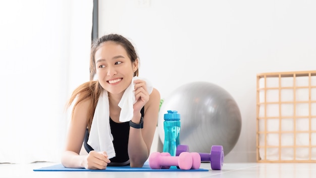 Asian women resting after play yoga and exercise at home background with copy space.Exercise for Lose weight, increase flexibility And tighten the shape.