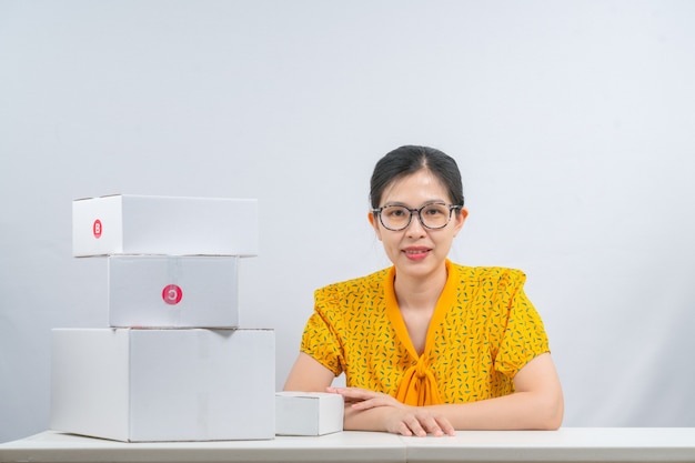 온라인으로 제품을 판매하는 아시아 여성은 주문이있는 고객에게 배달 할 수 있도록 양손으로 소포 상자를 들고 있습니다.