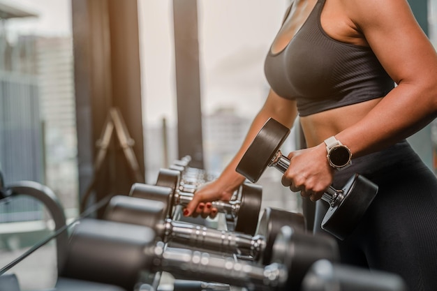 Photo asian women in sportswear working out with weights over exercise bench exercising are lifting dumbbells at fitness gym in the morningfitness muscular bodyfitness gym workout and healthy concepts