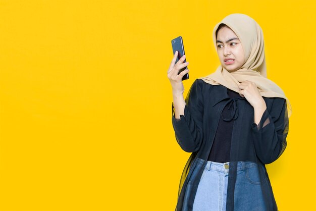 Foto le donne asiatiche parlano con lo smartphone sulla parete gialla