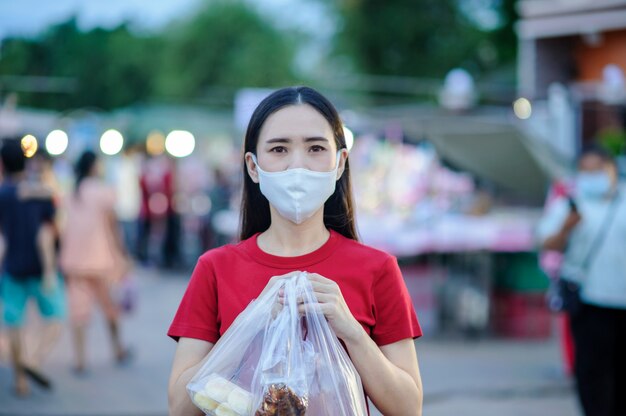 Азиатские женщины Тайцы используют лицевую маску или хирургическую маску для защиты от вируса короны, Covid 19, Новая нормальная жизнь людей в Юго-Восточной Азии, Тайские женщины используют маску на пешеходной улице