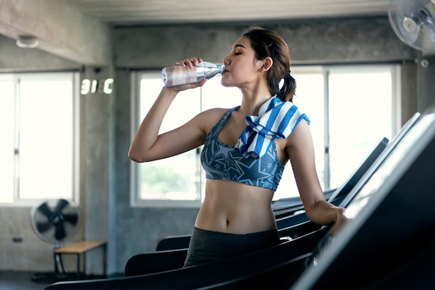 Asian women thirsty drinking water after exercise in fitness gym. healthy lifestyle.