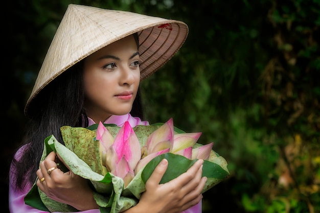 アジアの女性の伝統的なベトナムは蓮の花のバスケットの後に店に女の子トロリーバイクです。