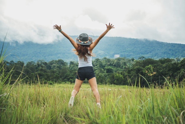 Asian women travel relax in the holiday. Jump on a green pasture.