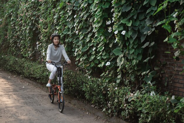 アジアの女性は折りたたみ自転車に乗るためにヘルメットを着用