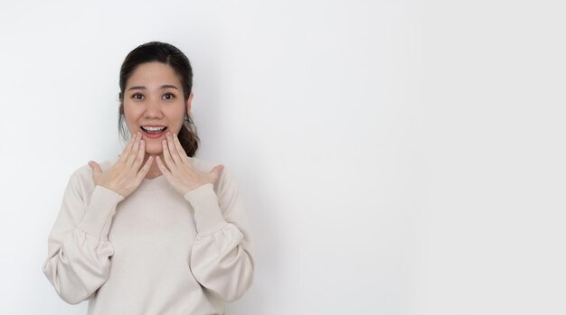 Le donne asiatiche indossano una maglietta bianca che usano la mano toccandosi il labbro con sorprese dalle notizie e dalla promozione con lo spazio della copia