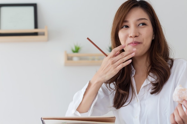 Le donne asiatiche lavorano a casa e mangiano spuntini