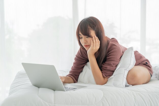 Asian women working with laptop on bed at home