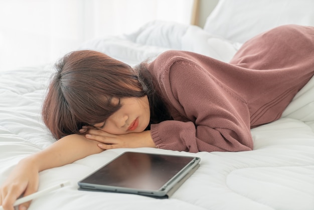 Asian women working with tablet on bed