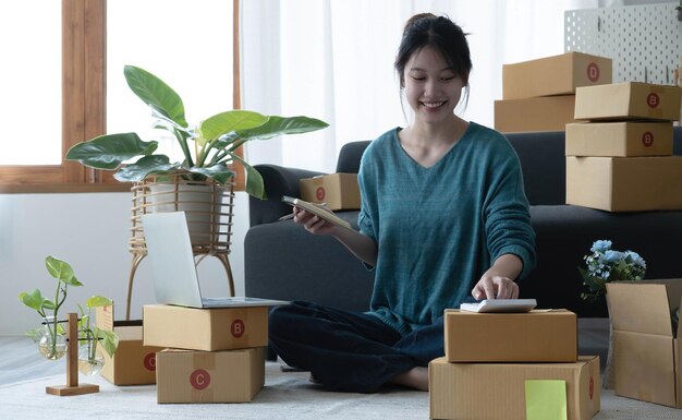 Asian women write note of orders of goods with a smiling face in concept of sme ecommerce business