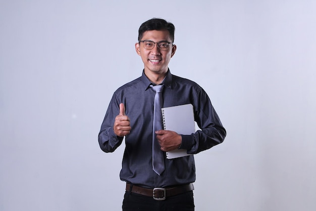 Asian worker holding notebook with smiling expression and giving thumbs up