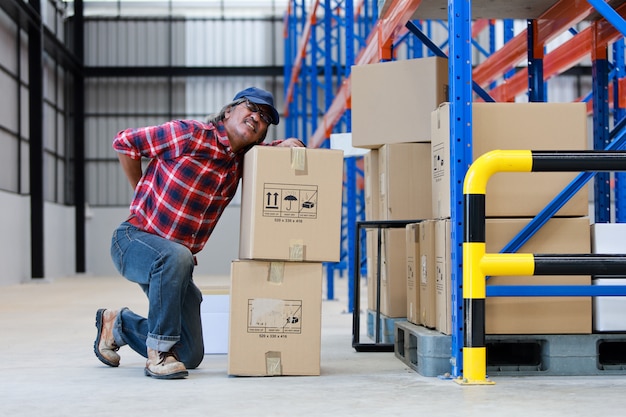 Photo asian worker man hurt his back lift heavy box in factory