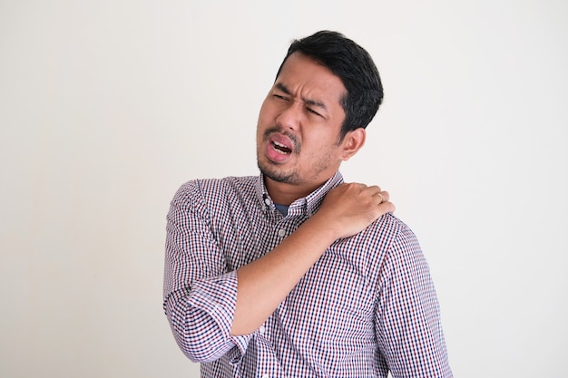 Asian worker man showing in pain gesture on his back shoulder