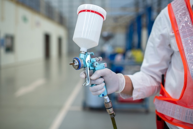 Asian workers stand to hold a spray gun in protective clothing