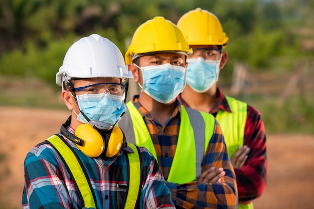 Азиатские рабочие носят защитные маски для безопасности на строительной площадке.