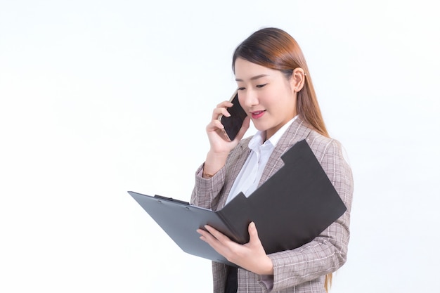Азиатская работающая женщина в строгом костюме с белой рубашкой звонит по телефону и открывает файл документа