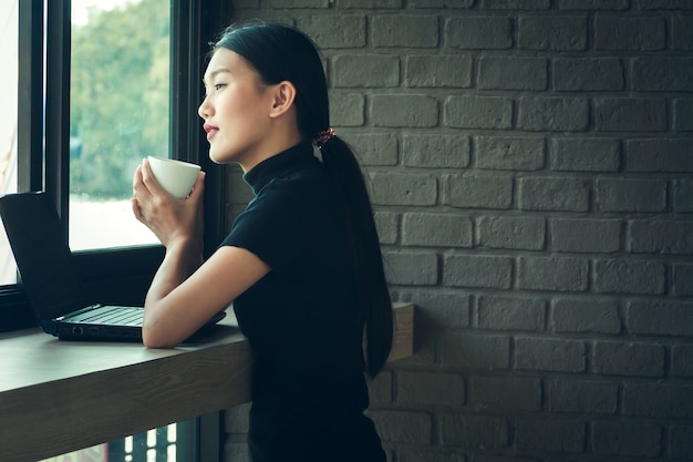 Asian working woman sit in coffee shop near the brick wall