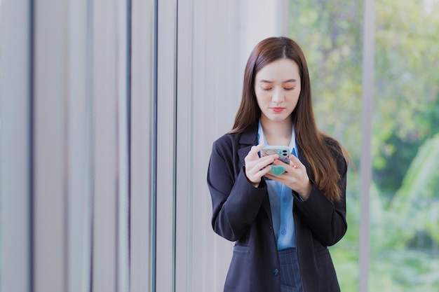 La donna lavoratrice asiatica usa lo smartphone per chattare con qualcuno nel concetto di digitalizzazione.