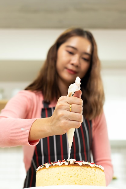 アジアの若い成人女性は、キッチンでベーカリー クッキング ケーキのオンライン コースを学ぶ方法を学ぶ