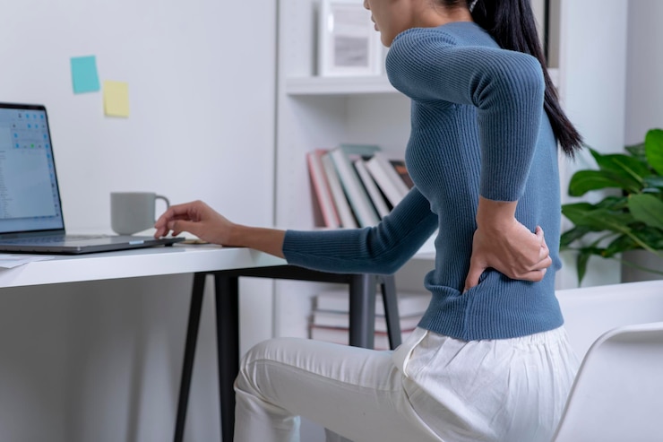 Photo コンピューター作業による背中の痛みを伴うアジアの若い魅力的な女性の痛み